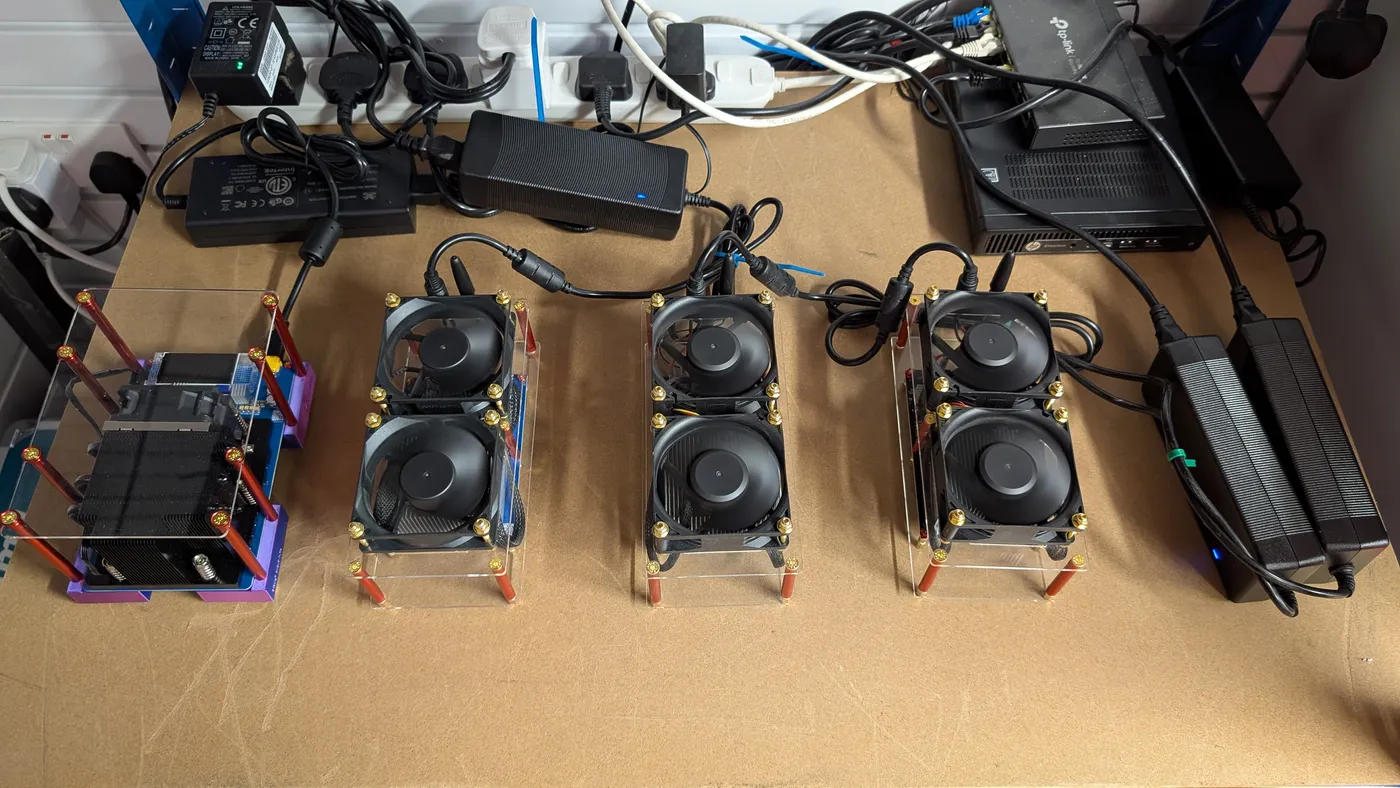 Three dual-fan Zyber miners and a single-board miner on a workbench, with power bricks, a network switch and a mini PC behind them