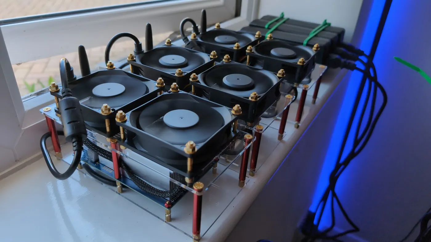 Two stacked multi-fan miners running on a windowsill in daylight
