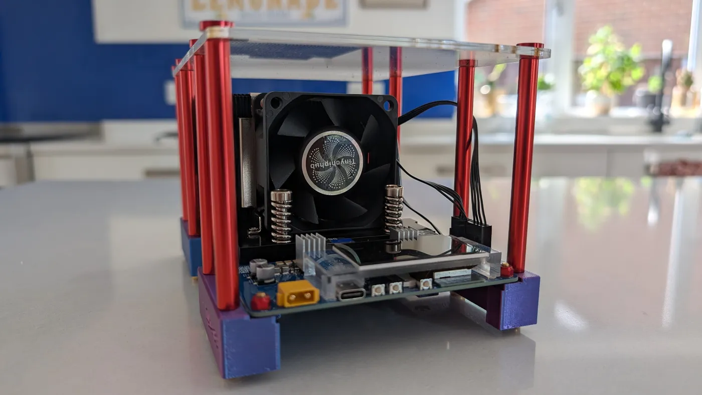 A TinyChipHub Zyber 8S open-frame miner on a kitchen worktop, showing the branded fan, XT60 power connector and status screen