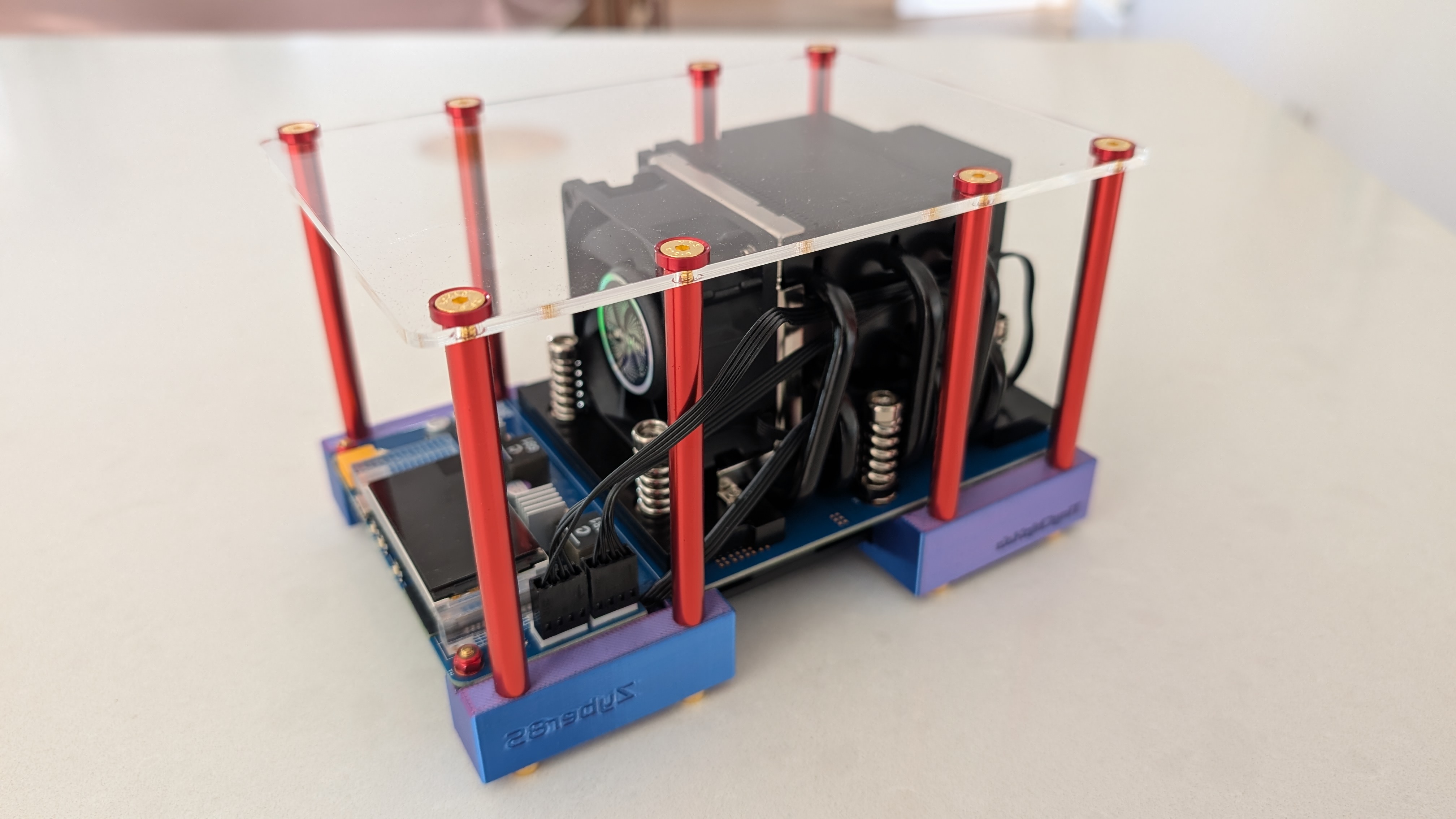 One of my solo Bitcoin miners - a Bitaxe-family board in an open acrylic frame with red standoffs and a tower heatsink, on the kitchen worktop